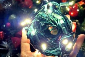 Hand holding a tangled bundle of green-wire Christmas lights.