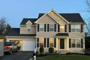 Christmas lights outline a two-story house beside a landscaping truck in the driveway.